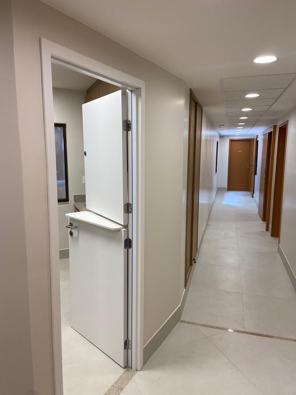 Um longo corredor com uma porta branca no meio