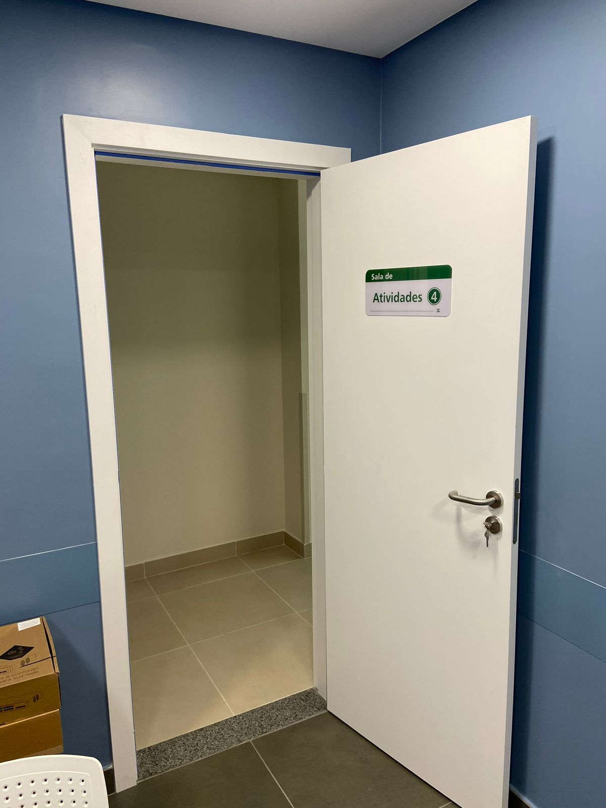 Uma porta branca está aberta em uma sala com paredes azuis.