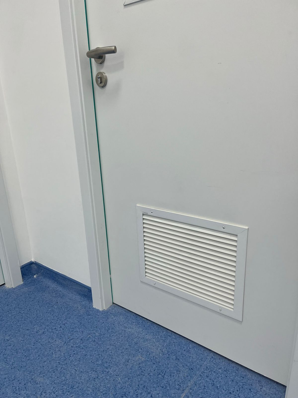Uma porta branca com uma ventilação na lateral.