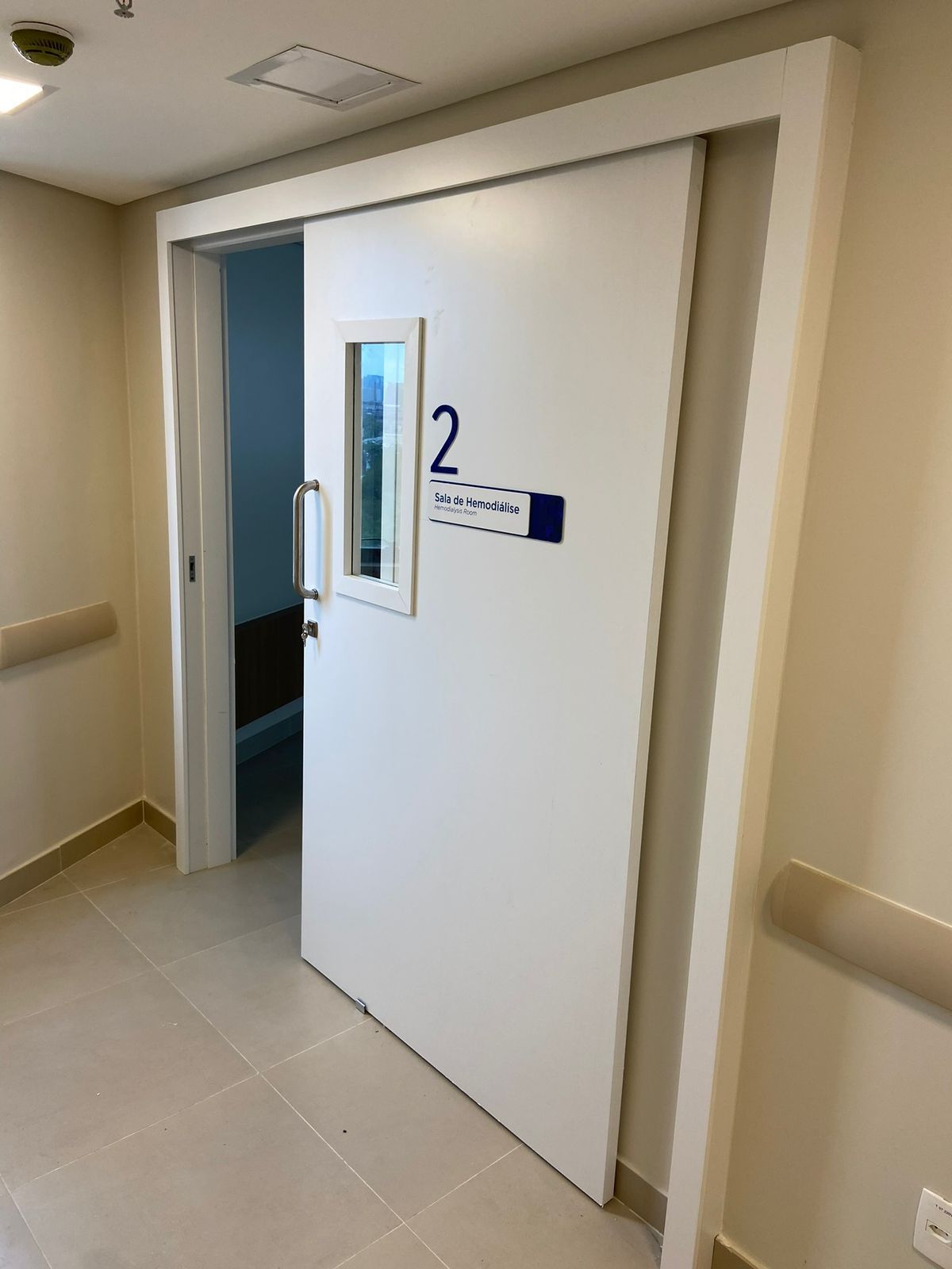 Um quarto de hospital com uma porta de correr e uma janela.