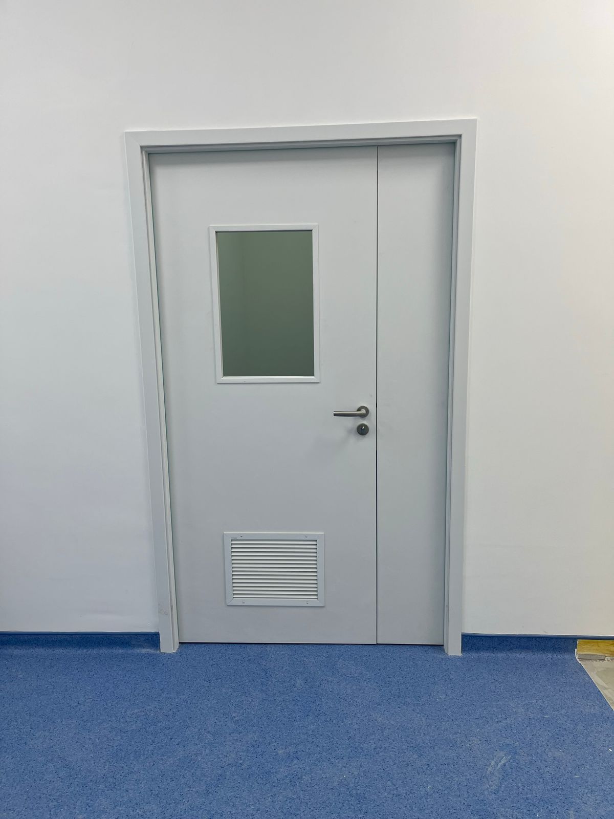 Uma porta branca com uma janela em uma sala com piso azul.