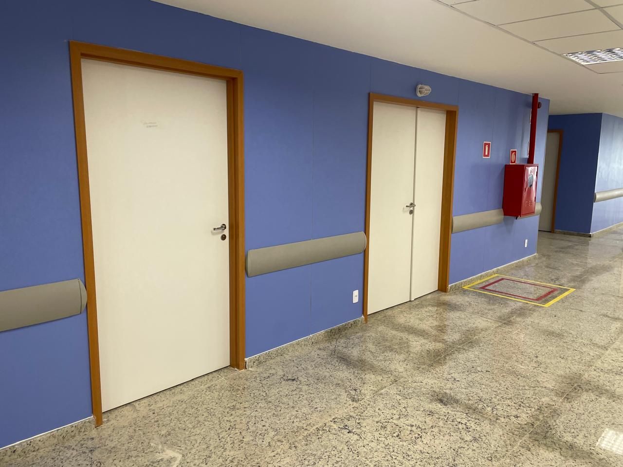 Um corredor de hospital com paredes azuis e portas brancas