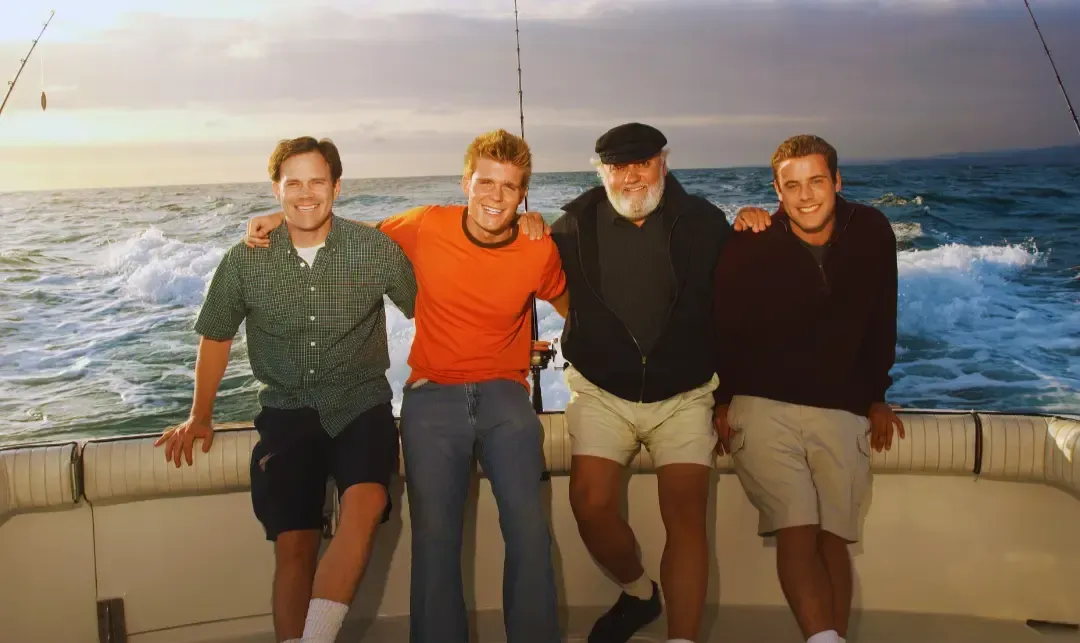 four men taking picture in a boat