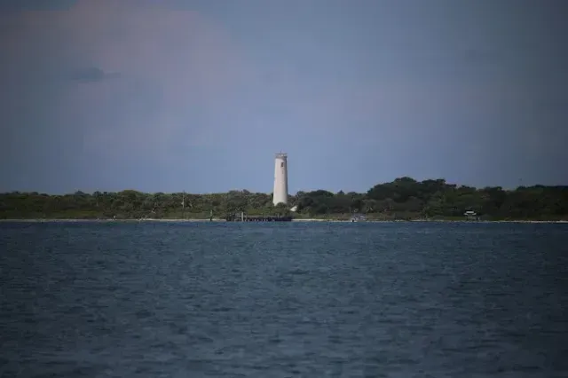 pontoon boat rental - A lighthouse is visible in the distance over a body of water.