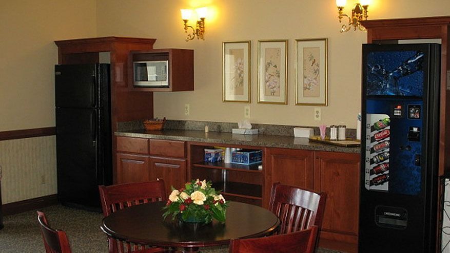 Lobby with round table and chairs, wood bar cabinet, framed art, wall sconces, and vending machine.