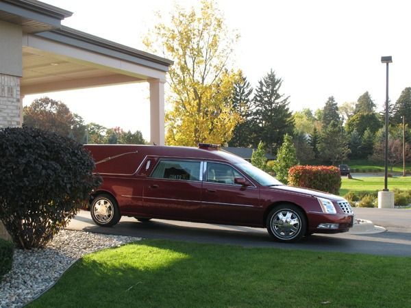 Maroon hearse parked outside a building on a sunny day
