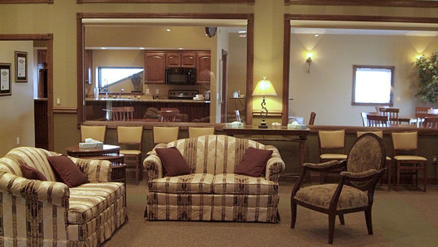 Warm lounge with striped sofas and chairs overlooking a dining area through a large interior opening.