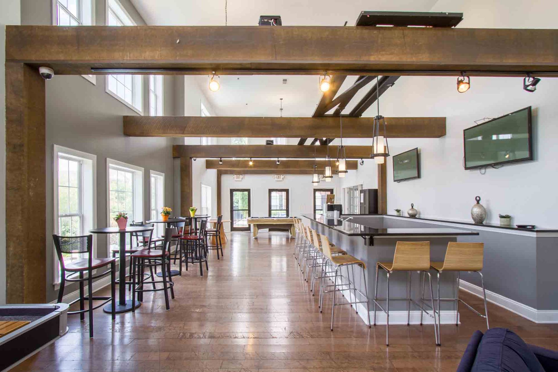 Spacious lounge with bar, tables, and a pool table. Large windows and wood beams at Hamburg Farms, offers apartments in Lexington, KY.