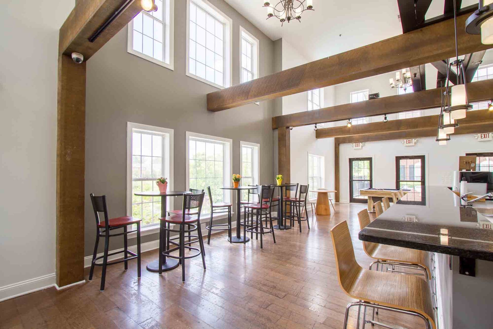 Spacious room with high ceilings, exposed beams, tall windows, tables, and bar seating at Hamburg Farms, offers apartments in Lexington, KY.