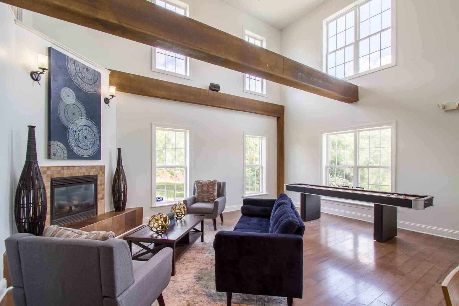 Spacious clubhouse with fireplace, high ceilings, large windows, dark wood beams and furniture, and a pool table at Hamburg Farms, offers apartments in Lexington, KY.