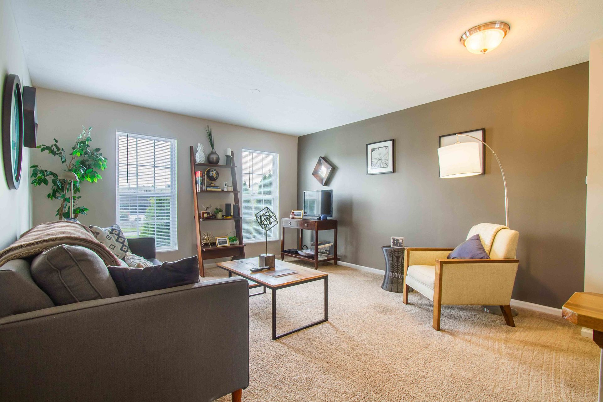 Living room with gray sofa, beige armchair, dark gray accent wall, and wood coffee table at Hamburg Farms, offers Lexington apartments for rent.