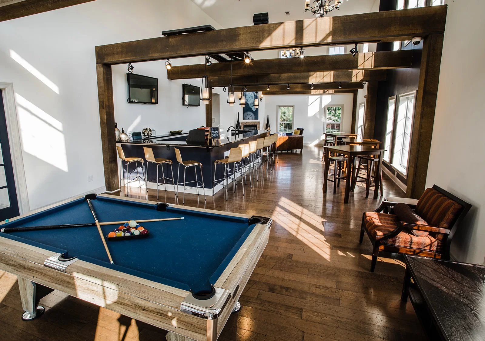 Pool table and bar area in a brightly lit room with wooden beams and seating at Hamburg Farms in Lexington.