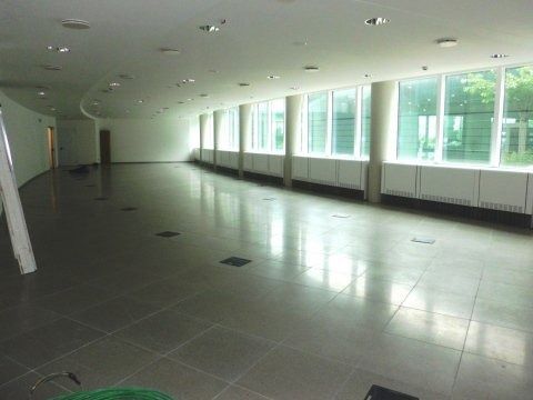 Corridoio moderno e vuoto, con pavimento piastrellato e grandi finestre lungo un lato