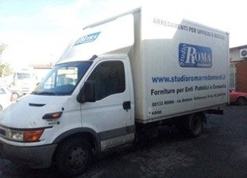Camioncino bianco con il logo Roma e una scritta in italiano, parcheggiato all’aperto