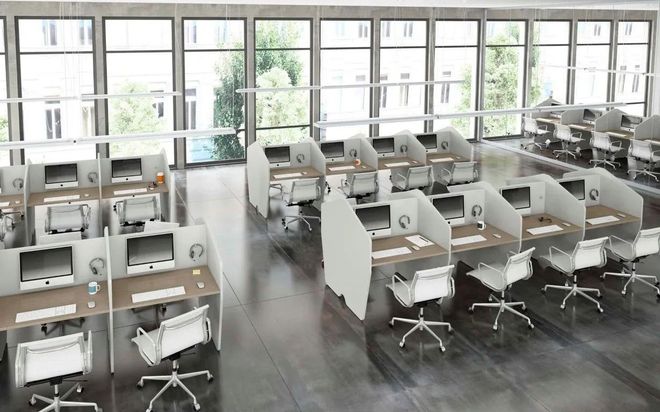 Ufficio open space con file di scrivanie bianche, computer e sedie girevoli vicino a grandi finestre