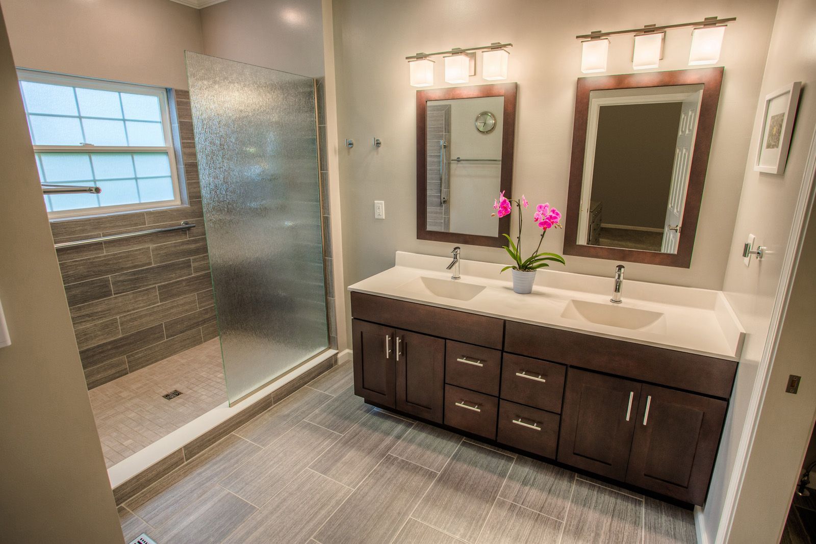 A bathroom with two sinks and a walk in shower.