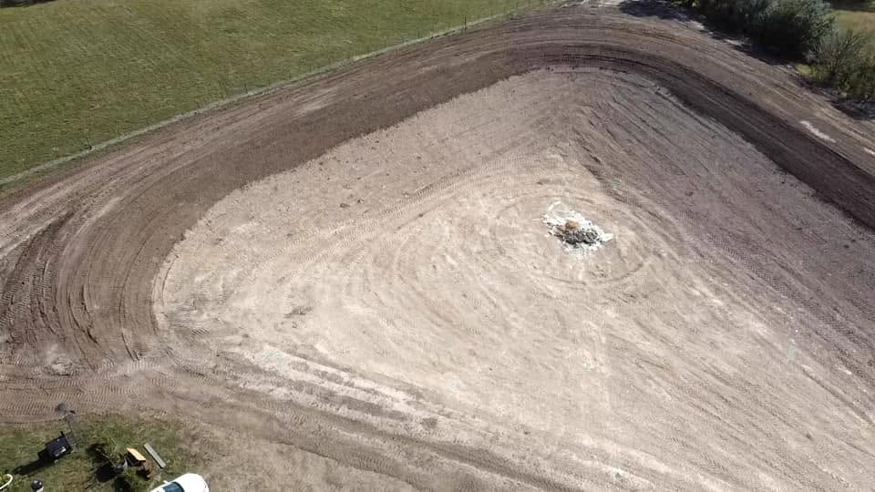 Aerial view of a large dirt mound or construction embankment with a small object near the center.