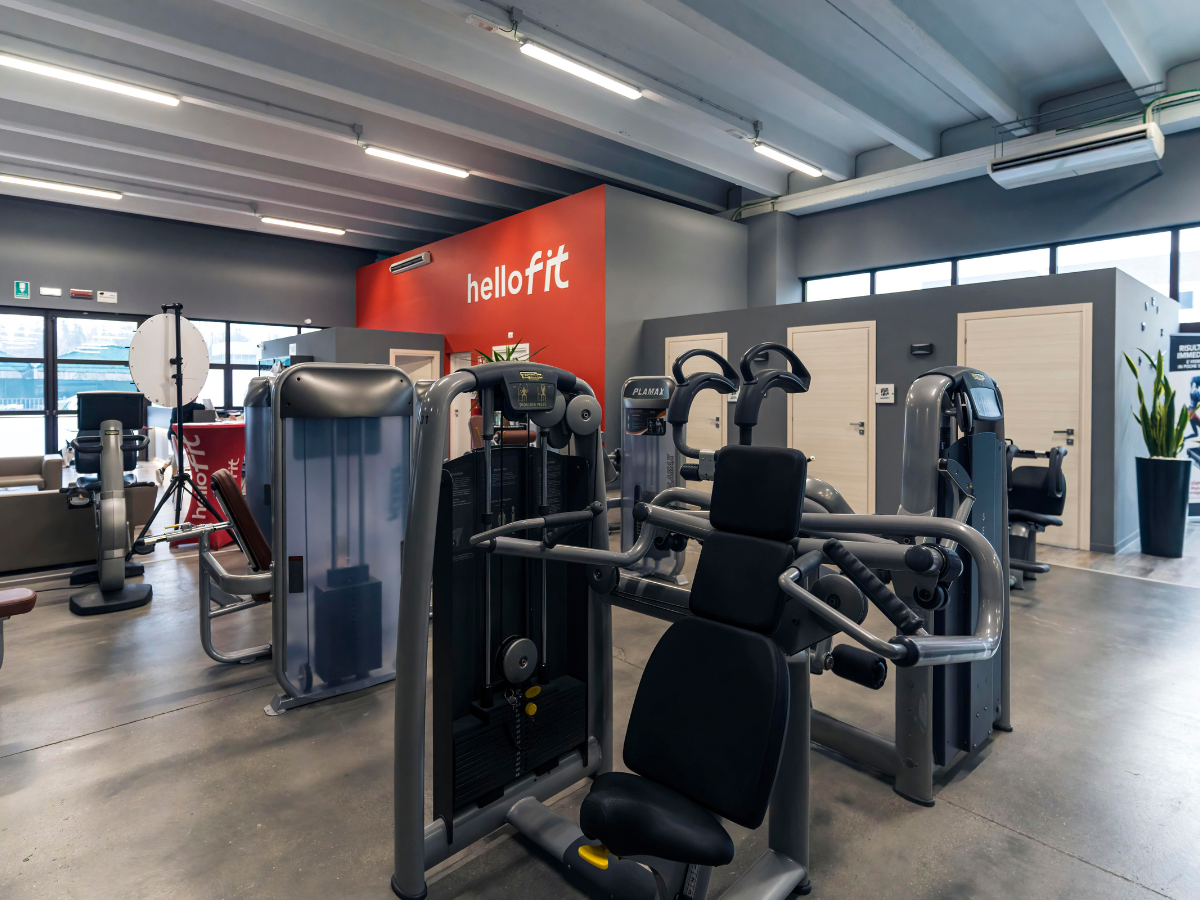 Interno della palestra con vari attrezzi ginnici e una parete rossa con il logo
