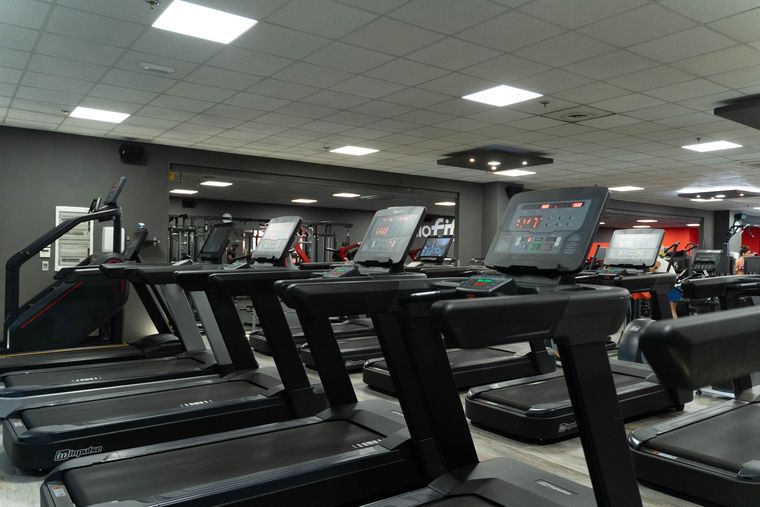 Interno della palestra con vari attrezzi ginnici e una parete rossa con il logo