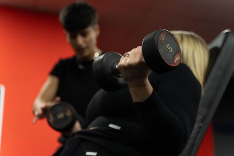 Tre persone in abbigliamento sportivo su cyclette; ambiente interno luminoso.
