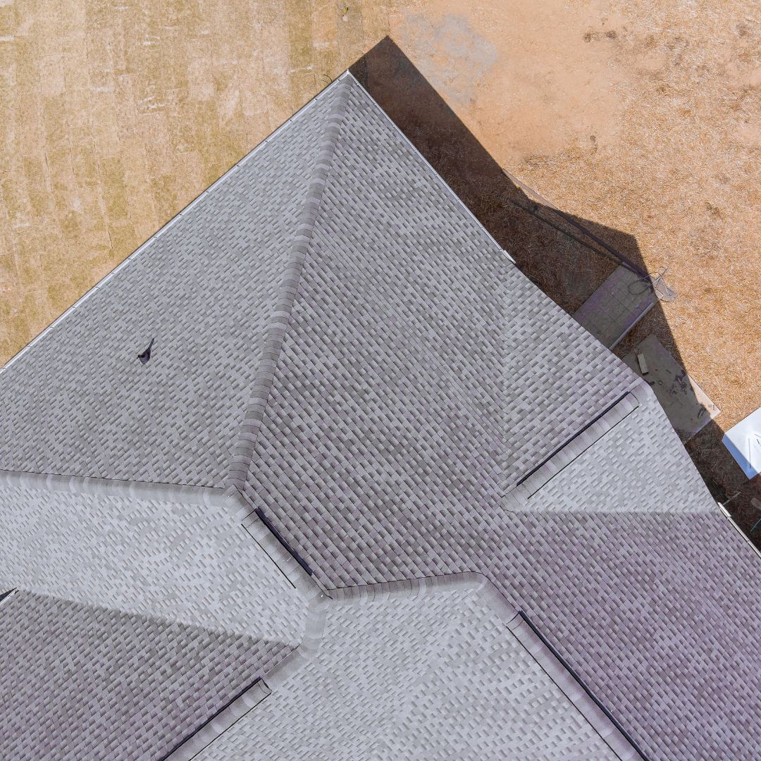 An aerial view of a roof with shingles being installed.