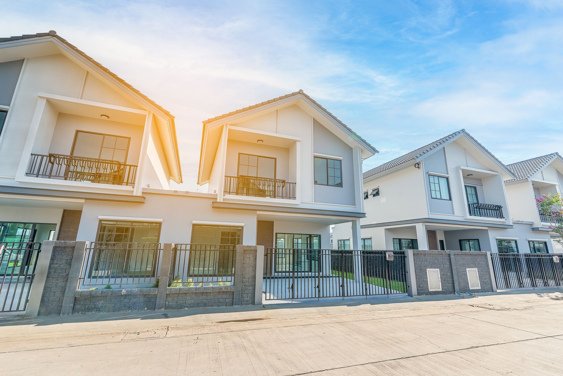 A row of white houses with a fence in front of them.