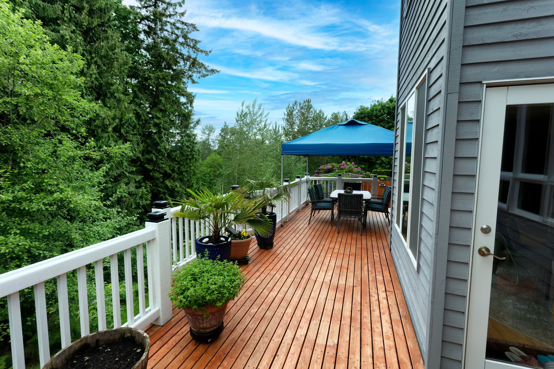A wooden deck with a white railing and a blue canopy