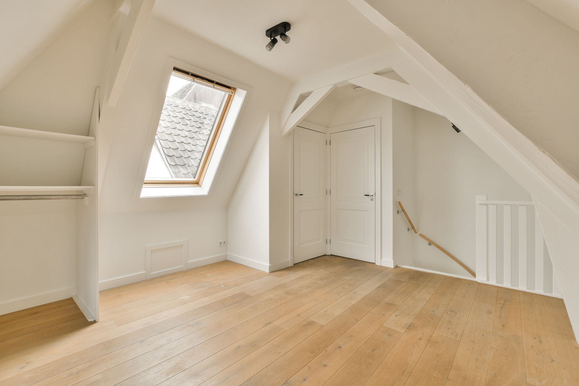 An empty attic with hardwood floors and a skylight