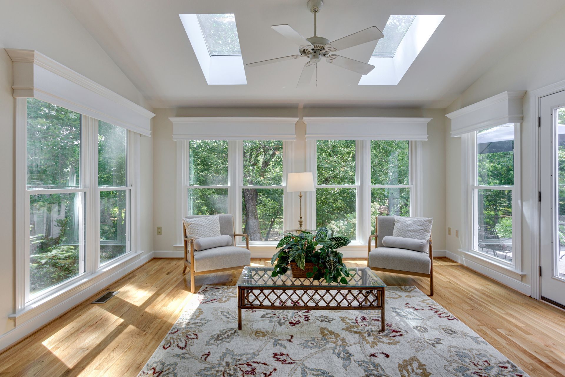 A living room with a lot of windows and a ceiling fan.