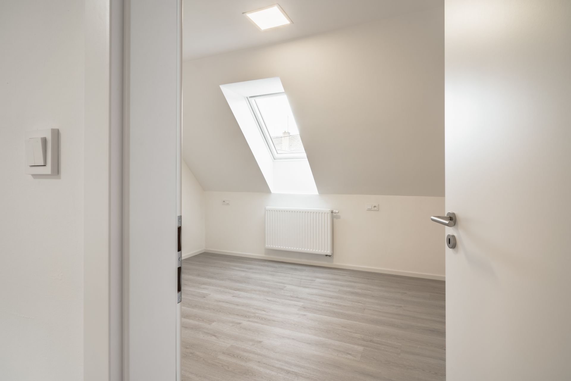 An empty room with a ceiling fan and a window.