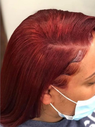 Woman with vibrant red hair, wearing a face mask. Hair is styled with laid baby hairs.