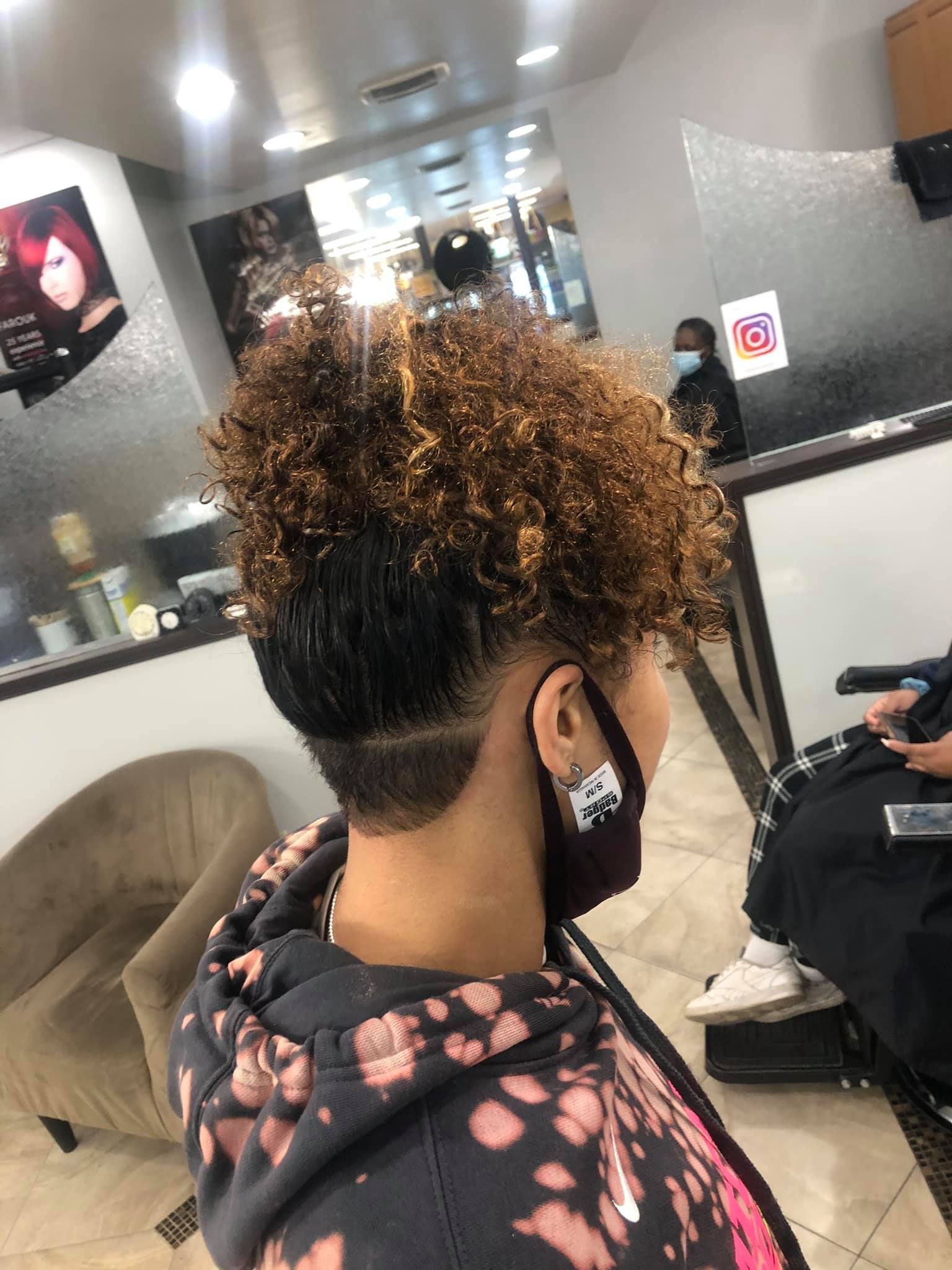 Person with curly brown hair and a dark undercut in a salon.