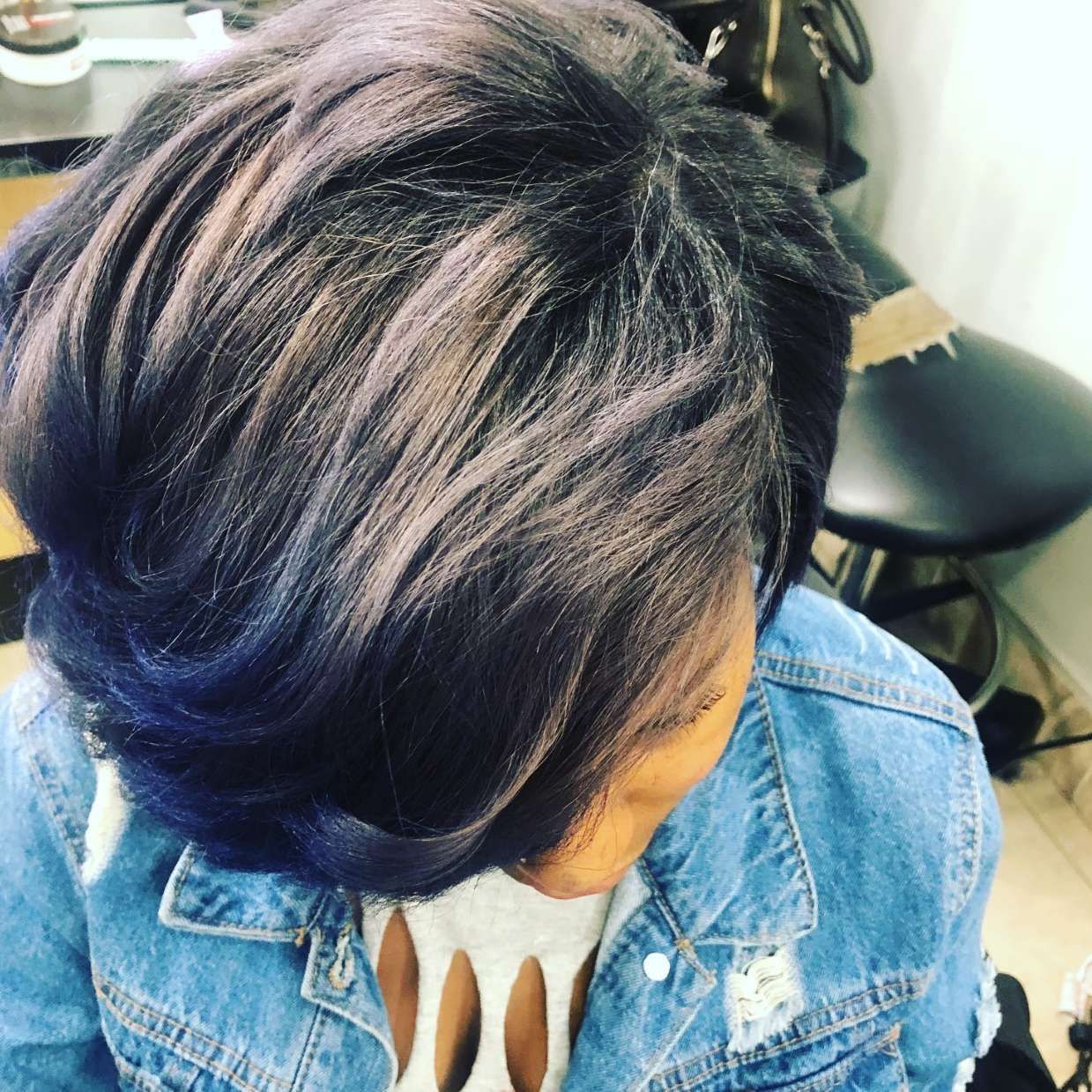 Woman with layered, dark hair, blue ombre tips, wearing a denim jacket.