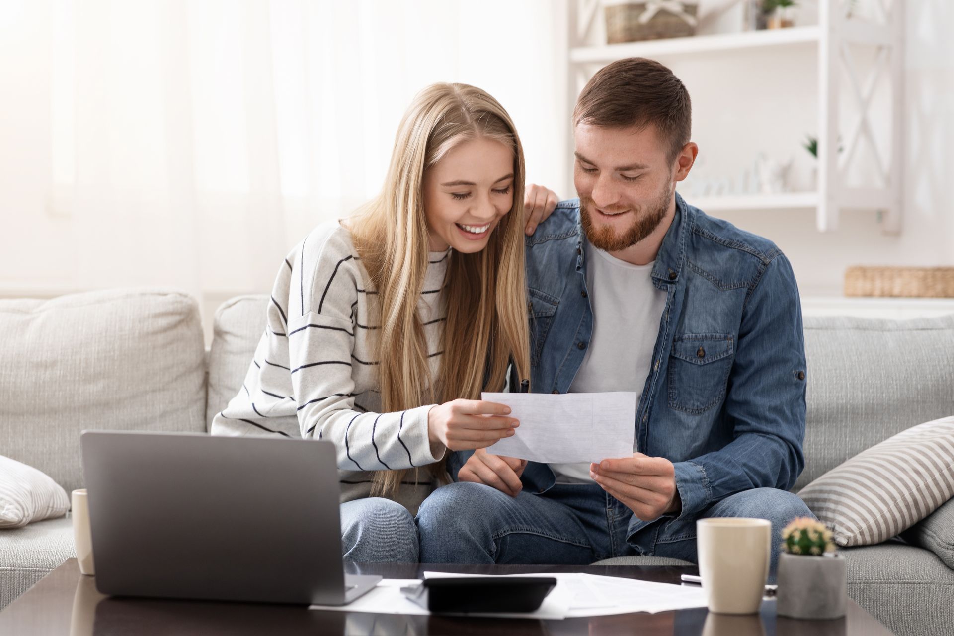 a man and a woman are sitting on a couch looking at a piece of paper