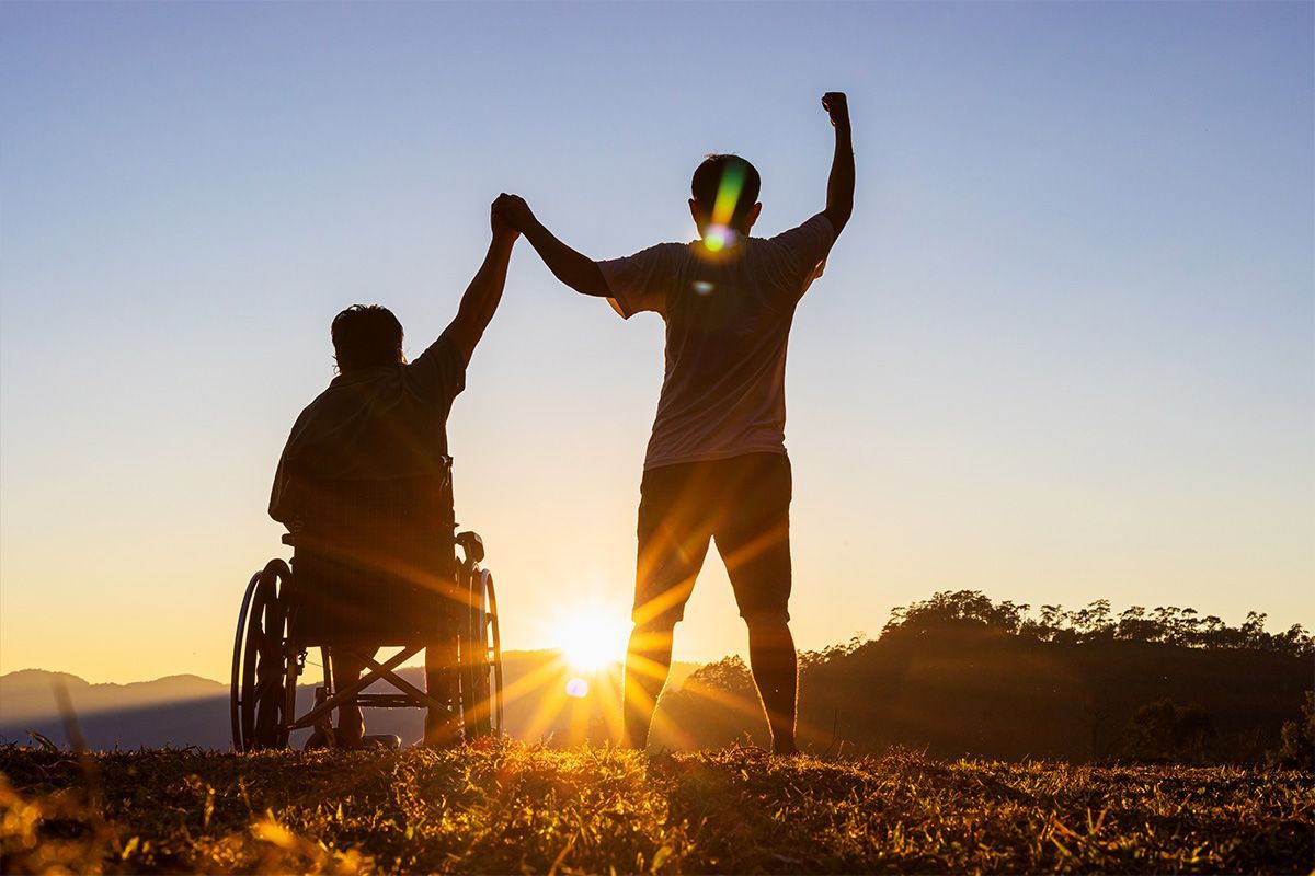A person in a wheelchair is holding hands with another person.