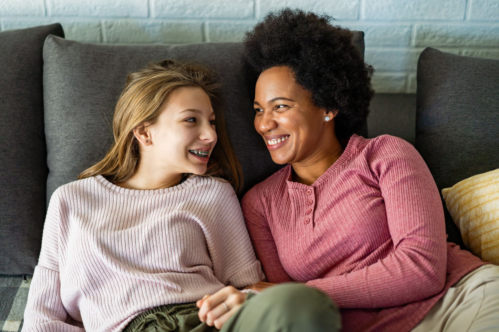 a mother and daughter are lying on a couch talking to each other