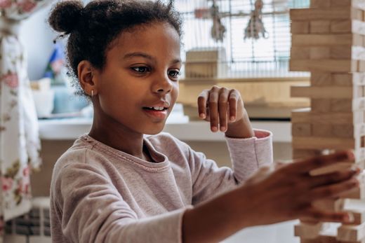 a young girl is playing with wooden blocks on a table