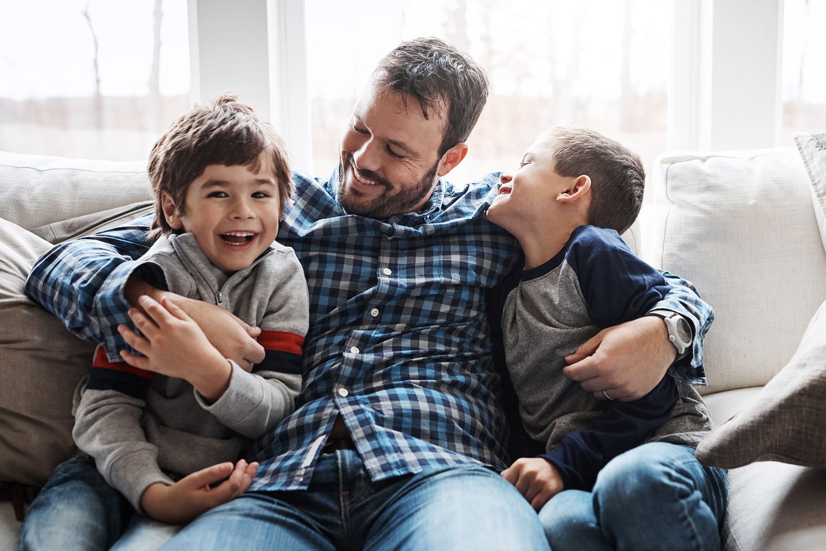 A father sitting on a couch with his two boys.