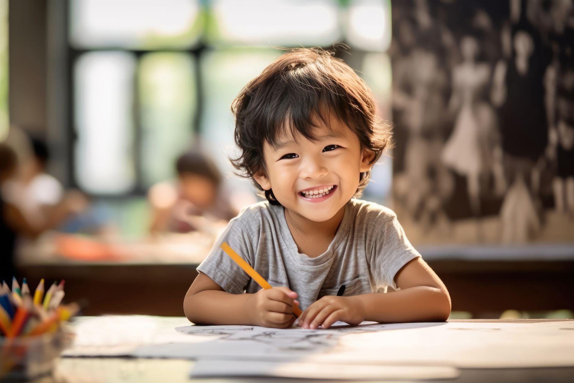 a little boy is sitting at a table drawing with a pencil