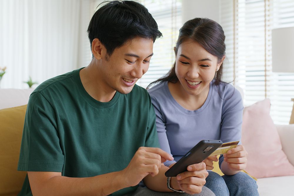 a man and a woman are sitting on a couch looking at a phone