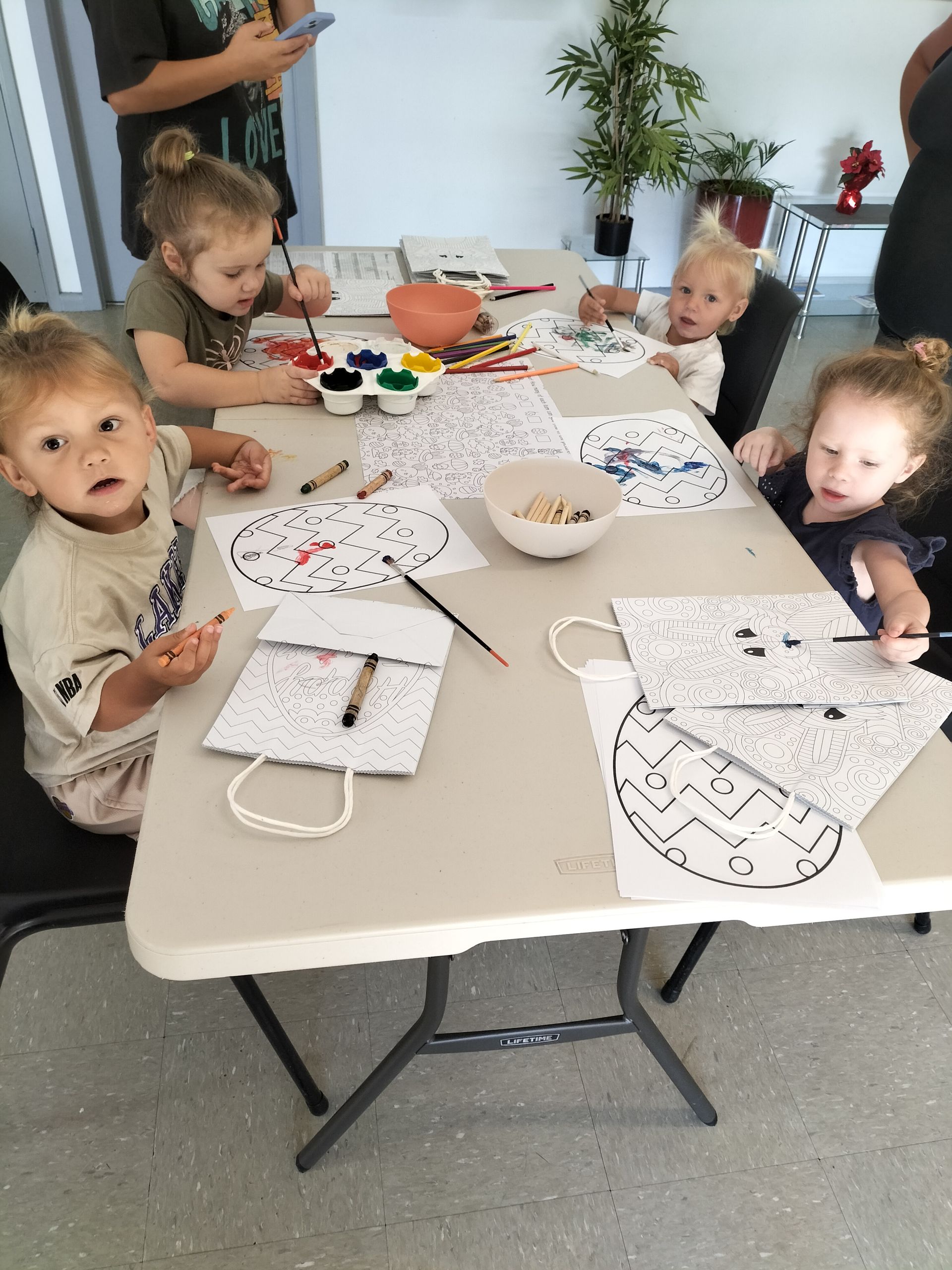a group of young children are sitting at a table painting