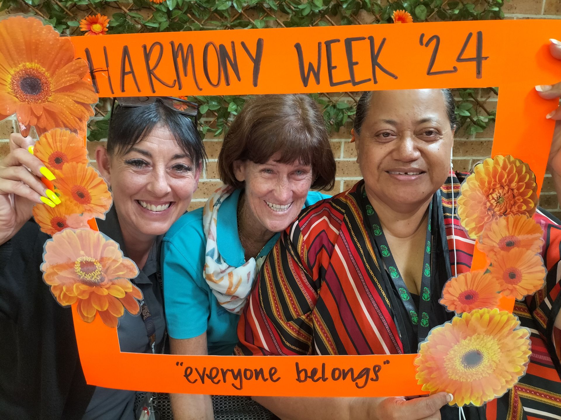 a group of women holding a frame that says Harmony Week 24
