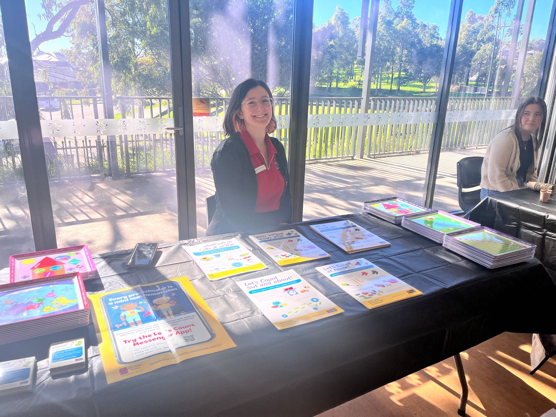 a woman is sitting at a table with a lot of books on it