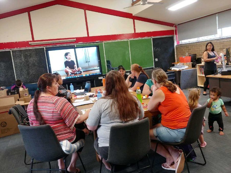 a group of people sitting around a table in front of a television