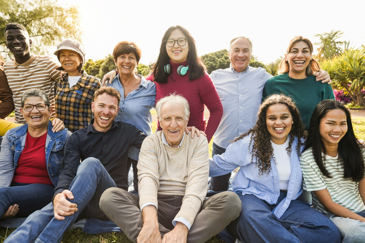 Multi-generational group of volunteers and seniors smiling together outdoors