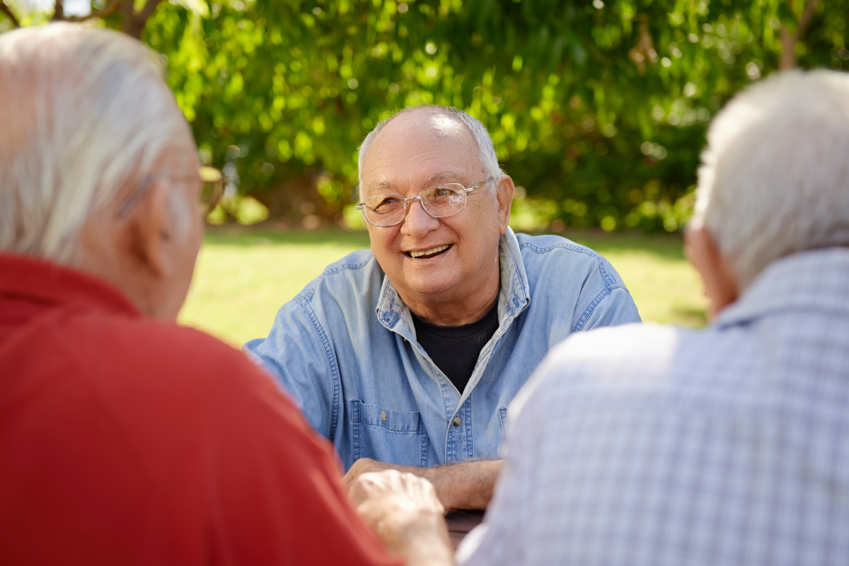 Senior men chatting and laughing together outdoors at a Multicultural Group session