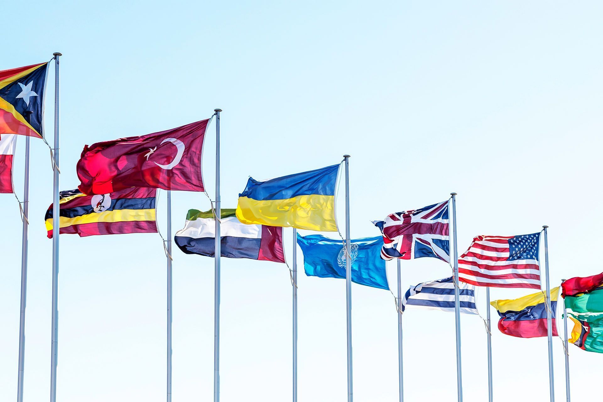A row of flags from different countries are waving in the wind.