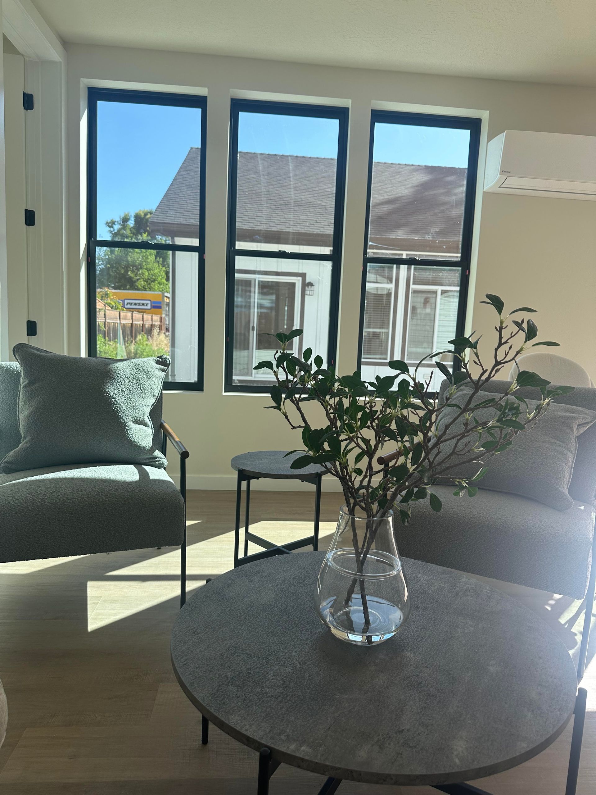 Perpetual Homes ADU: Living room with gray furniture, round coffee table, and three large windows.