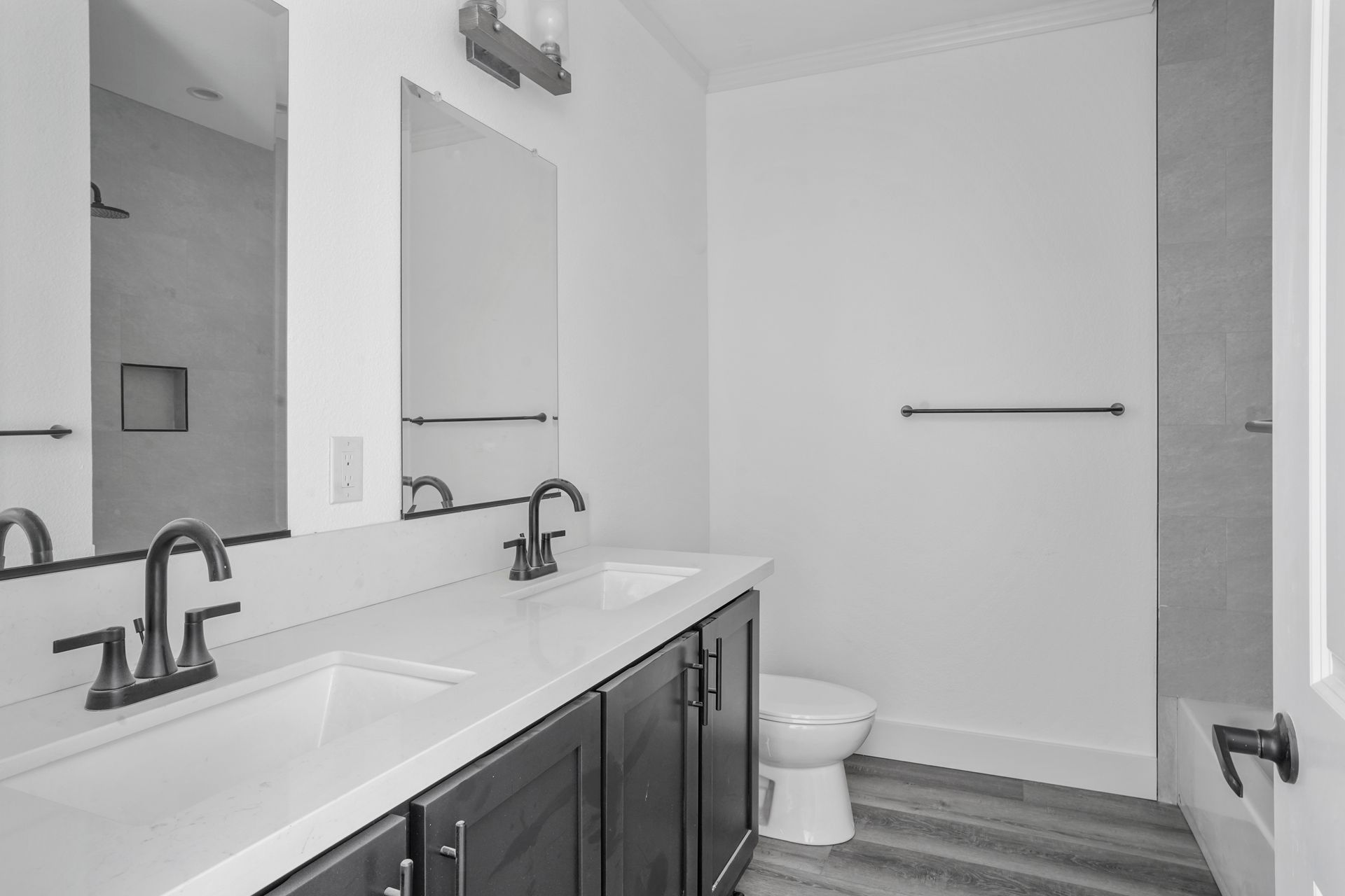 Perpetual Homes ADU: Bathroom with white walls, double sinks, dark cabinets, and a toilet.