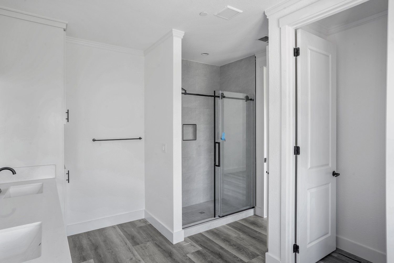 Perpetual Homes ADU: Bathroom interior with a shower, door, towel rack, and wood-look flooring.
